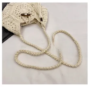 Détail du sac bandoulière tissé blanc cassé avec bouton en bois et glands décoratifs