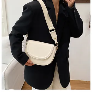 Chic beige saddle bag with wide canvas strap shown on a model in a minimalist setting