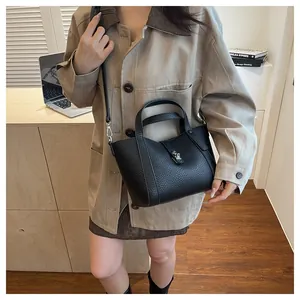 Détail du sac en cuir noir motif litchi avec fermoir métallique et bandoulière