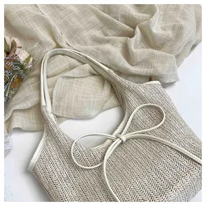 Détail du sac cabas en paille crème avec grand nœud blanc et texture en chevrons