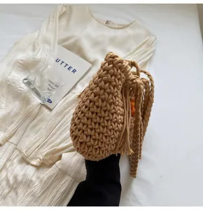 Detailed view of a brown crochet tote bag with fringe accents and braided handles