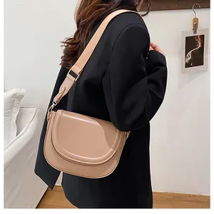 Detail of minimalist beige saddle bag with wide fabric strap on black blazer