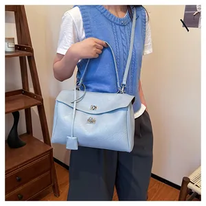 Détail du sac à main en cuir bleu clair avec fermoir rotatif argenté et plusieurs bandoulières