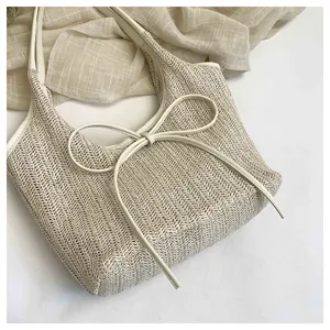 Détail du sac cabas en paille tressée avec nœud en cuir blanc et motif en zigzag