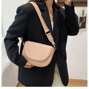 Detailed view of beige saddle bag with wide canvas strap against a black blazer