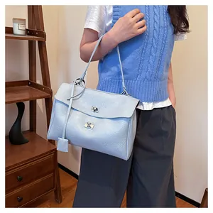 Détail d'un sac à main bleu clair texturé avec fermoir rotatif argenté et rabat élégant