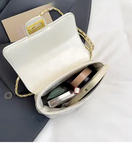 Vue détaillée de l'intérieur d'un sac blanc matelassé avec chaîne dorée et espace de rangement