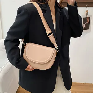 Minimalist beige saddle bag for women with wide shoulder strap and gold hardware
