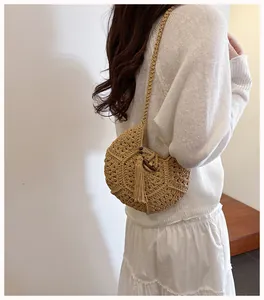 Détail du sac bandoulière en paille tressée avec pompon et fermoir en bois naturel