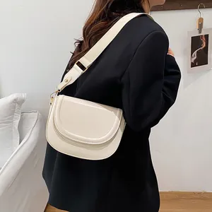 Minimalist cream white saddle bag with wide shoulder strap and gold hardware accents