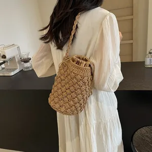Handwoven khaki bucket bag with drawstring closure and spiral strap for beach vacation