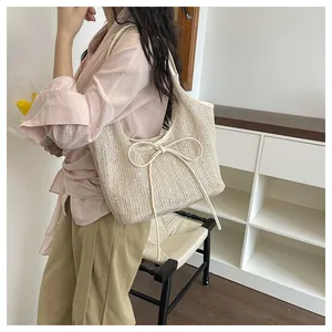 Vue détaillée du sac en paille beige orné d'un grand nœud et d'une texture tissée fine