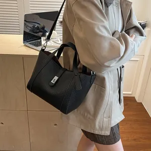 Sac seau classique en cuir noir à motif litchi avec boucle en métal argenté sur bureau