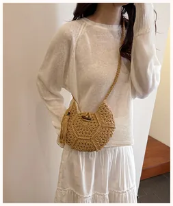 Détail du sac bandoulière en paille tressé avec de longs pompons et bouton en bois