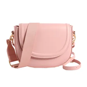Pink PU leather saddle bag with wide fabric strap and golden hardware on white background
