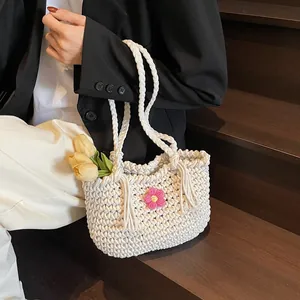 White woven tote bag with a pink flower detail and tassels for beach vacations