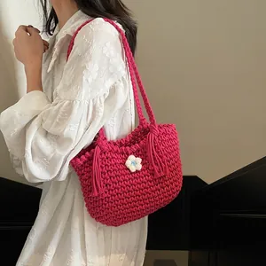 Handmade magenta crochet tote bag with white flower and tassels on white dress model
