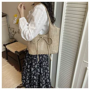 Détail d'un sac cabas en paille avec un grand nœud décoratif et bordure en cuir