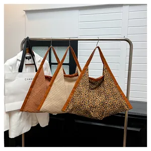 Detailed view of woven and leopard print tote bags hanging on a rack for display