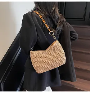 Dettaglio borsa a spalla in paglia con catena in resina ambrata e anelli metallici