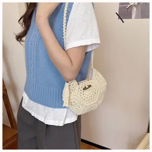 Détail du sac bandoulière tissé avec motifs floraux, glands et fermeture en bois