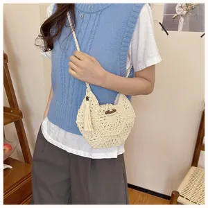 Détail d'un sac bandoulière tissé avec perles en bois et pompons pour les vacances