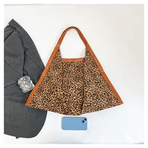 Close-up of leopard print tote bag with brown leather handles and textured fabric detail