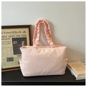 Detail of pink quilted tote bag showing ruffled shoulder straps and side pocket texture