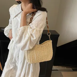 Borsa sottobraccio in paglia beige con catena dorata e anelli in resina ambra da spiaggia