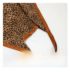 Detailed shot of brown leather handles and leopard print texture on this tote bag