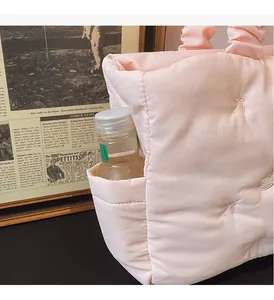 Detail of light pink quilted tote bag with side pocket holding a water bottle
