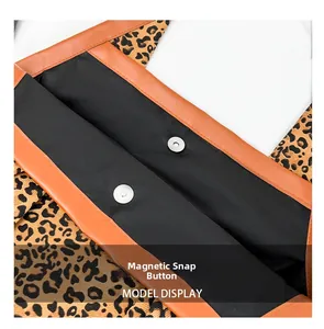 Detail of the magnetic closure on a leopard print canvas tote bag with brown leather trim