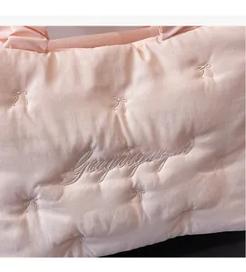 Detailed close-up of light pink quilted tote bag featuring bow stitching and embroidery