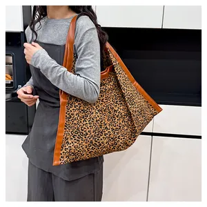 Detailed shot of large leopard print tote bag with brown leather handles worn by a model