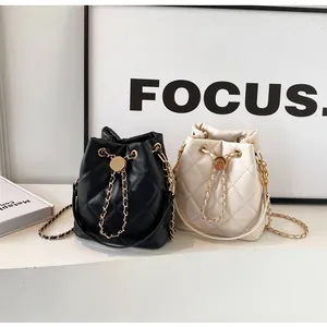 Detail view of black and cream quilted bucket bags with gold chain drawstring and hardware