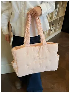 Detail of light pink quilted nylon tote with bow embroidery and ruffled handle design