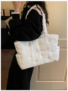 Detail of white quilted nylon tote bag with embroidery and ruffled shoulder straps