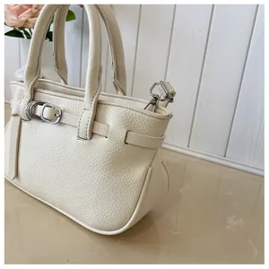 Détail d'un sac à main beige en cuir grainé avec boucles argentées et bandoulière