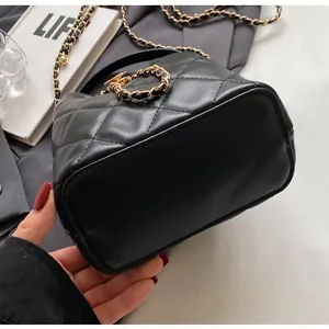 Detail of black quilted bucket bag featuring elegant gold chain strap and smooth oval base