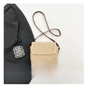 Close-up of beige woven straw crossbody bag with brown leather strap and size reference