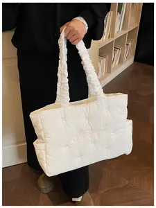 Detailed embroidery of pink bows and logo on a quilted white puff shoulder bag