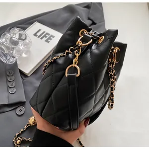 Close-up of black quilted leather bucket bag with gold chain strap and side detail