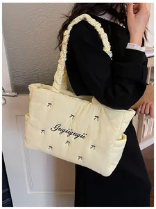 Detailed embroidery on a quilted cream puff tote bag with elegant bow patterns