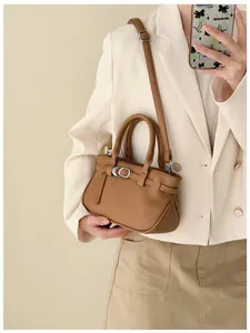 Détail du sac à main en cuir grainé marron avec boucle dorée et bandoulière réglable