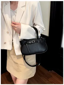 Détail du sac à main en cuir grainé noir avec boucle métallique et décor de sangle