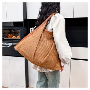 Close-up of a large woven tote bag in brown straw material on a shoulder for daily use