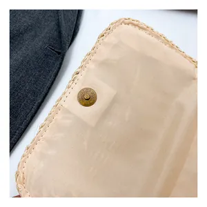 Detailed close-up of straw woven bag with magnetic snap button and textile lining