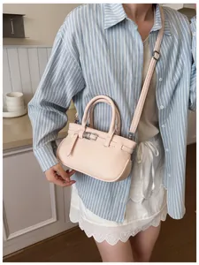 Gros plan du sac à main en cuir rose clair avec texture sur le bras d'un mannequin en scène