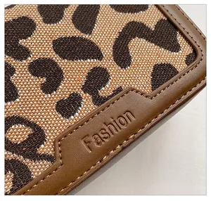 Dettaglio del tessuto leopardato con finiture in pelle marrone e logo Fashion impresso