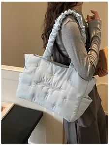 Close-up of light blue quilted tote bag with bow embroidery and ruffled shoulder strap